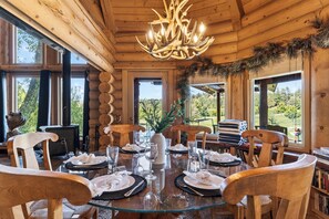 A wooden cabin interior with a round dining table set for six, surrounded by wooden chairs. - Hot Tub + Pool Table + Views | Bear Mountain + Lake | Moonshadows Log Cabin (Big Bear Lake)
