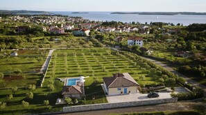 An aerial view of a residential area with houses, a swimming pool, and a large body of water in the background. - Villa Evelyn by Villas Guide (Fažana)