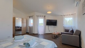 Ein Hotelzimmer mit Bett, einer Couch, einem Fernseher und einem Balkon.