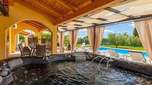 Ein Whirlpool mit fließendem Wasser, umgeben von Sitzgelegenheiten im Freien und einem Pool.