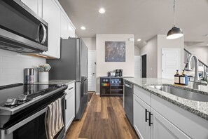 Eine moderne Küche mit Mikrowelle, Herd, Kühlschrank und Kaffeemaschine.