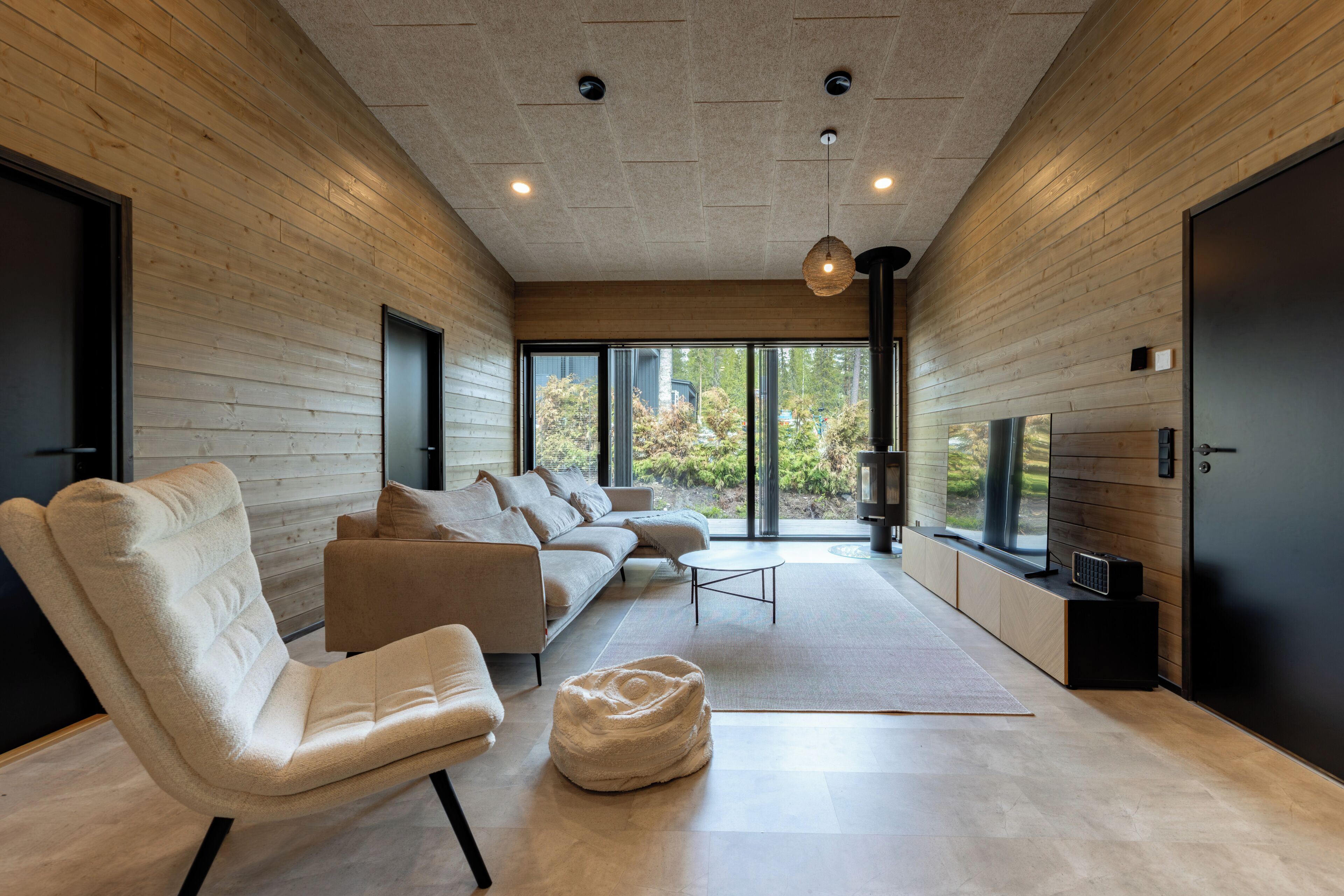 A modern living room with a sofa, chairs, a coffee table, and a television.