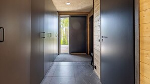 A hallway with a modern design, featuring a dark door, a light-colored wall, and a textured ceiling. - Villa Noel A  (Lappi)