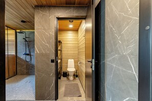 A modern bathroom with a wooden shower enclosure, a marble-tiled floor, and a visible toilet.