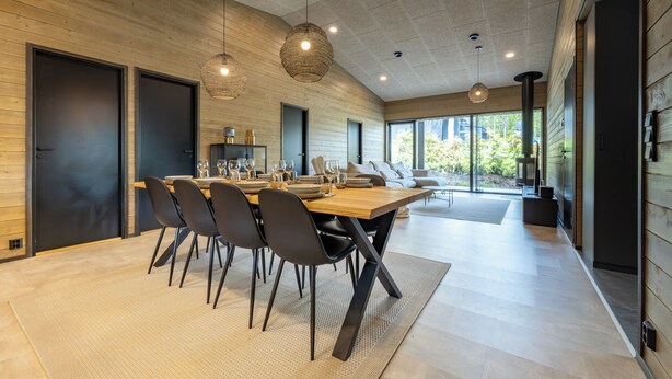 A modern dining area with a wooden table, black chairs, and hanging lights. - Villa Noel A  (Lappi)