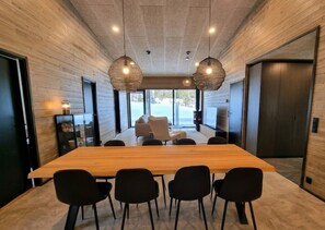 Ein modernes Interieur mit einem langen Holztisch, schwarzen Stühlen und gewebten Pendelleuchten.