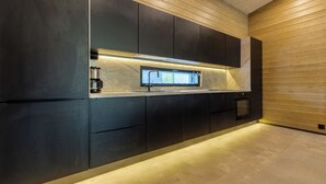 A modern kitchen with dark cabinetry, a built-in oven, and a window above the sink. - Villa Noel A  (Lappi)