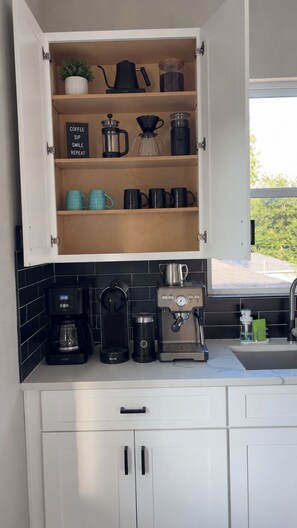 Une cuisine équipée d’un coin café, comprenant une machine à café, un moulin à caf é et des tasses.