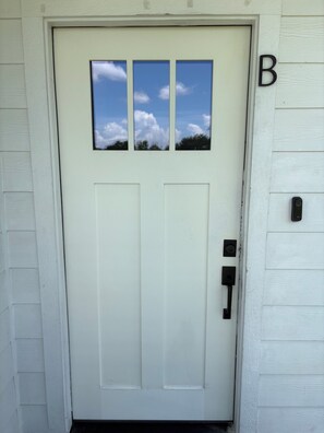 A white door with a small window, a mailbox, and a house number 'B' on the wall. -      The Haven House  A Peaceful Escape for Every Traveler (Houston)