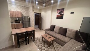 Un espacio habitable compacto con kitchenette, comedor, sofá y televisor.