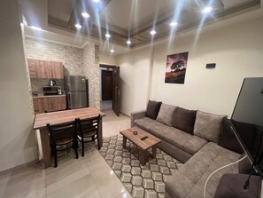 Um espaço compacto com cozinha compacta, área de refeições, sofá e televisão.