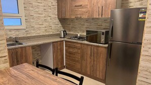 Una cocina con microondas integrado, refrigerador de acero inoxidable y una mesa de madera.