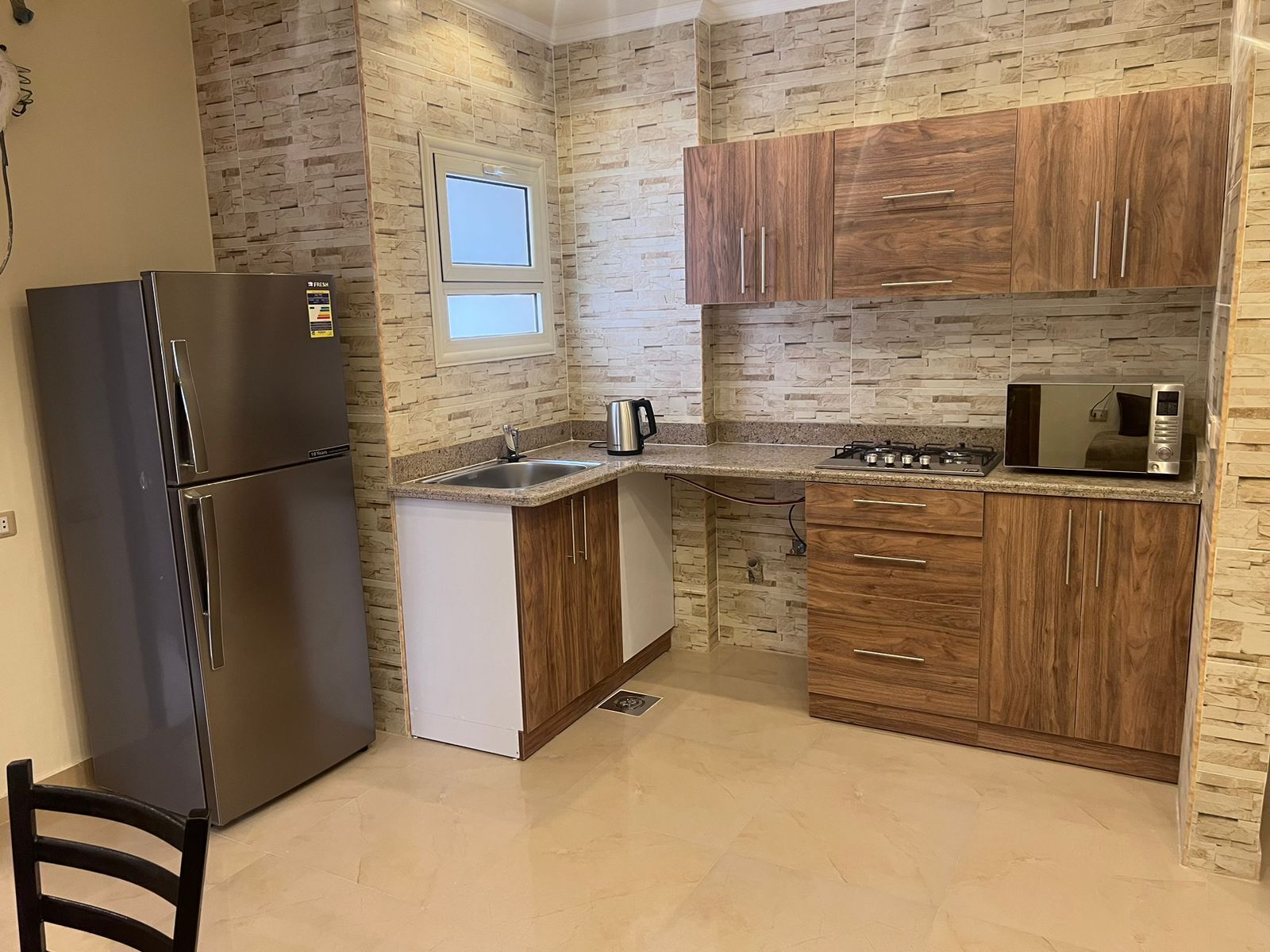A kitchen with a refrigerator, stove, microwave, and wooden cabinets.