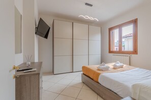 Ein Schlafzimmer mit Bett, Kleiderschrank, einem an der Wand befestigten Fernseher und einem Fenster mit Blick.