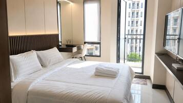 A modern hotel room with a large bed, a desk, a chair, and a TV.