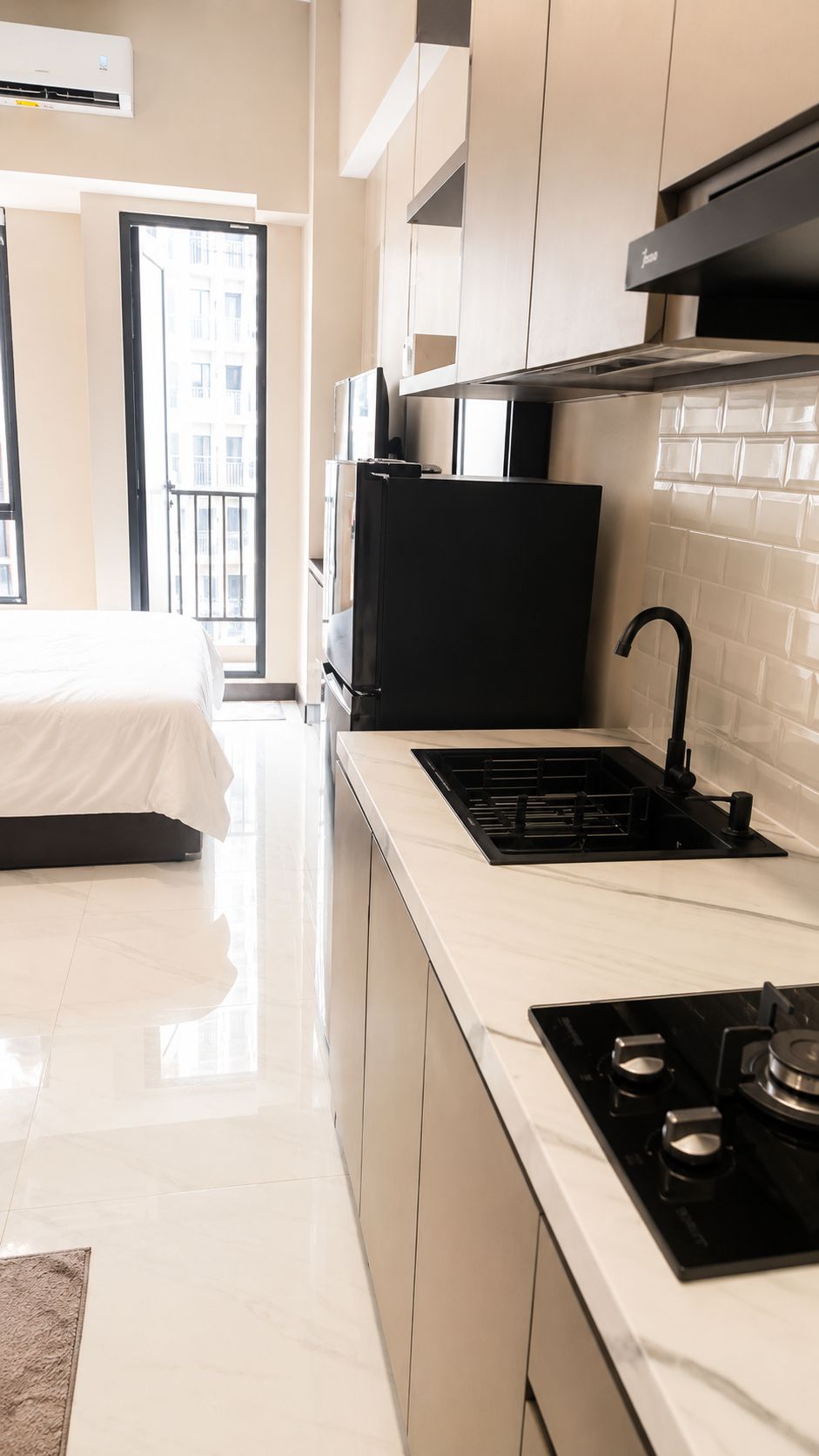 A modern kitchen with a black stove, a sink, and a window overlooking a balcony.