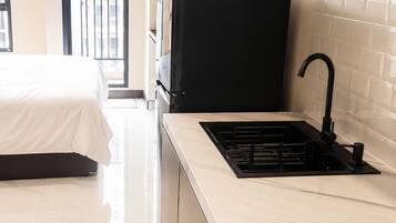 A modern kitchen with a black stove, a sink, and a window overlooking a balcony.