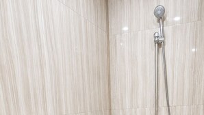 Un baño con ducha, inodoro y suelo de baldosas.