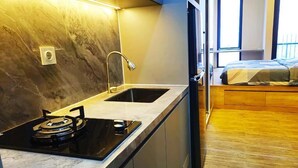 Una cocina compacta con estufa a gas, lavamanos y una pequeña ventana.