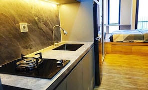 A compact kitchen with a gas stove, sink, and a small window. - Apartement Pakuwon By 21Room (Jawa Barat)