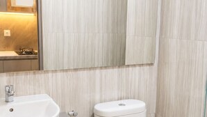 A modern bathroom with a round sink, a toilet, and a mirror above the sink. - Apartmen Pakuwon by Fiola Homes (Jawa Barat)