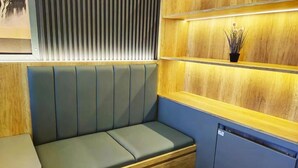 Un espacio de descanso con un banco, paneles de madera y una planta pequeña en un estante.