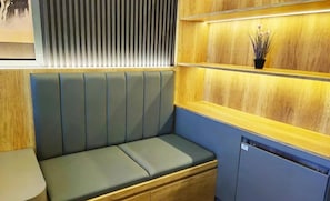 A seating area with a bench, wooden paneling, and a small plant on a shelf. - Apartement Pakuwon By 21Room (Jawa Barat)