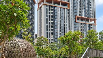 Un edificio residencial moderno con piscina, rodeado de vegetación y un paseo cubierto.