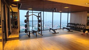 Un gimnasio con equipo de levantamiento de pesas, una banca y mancuernas.