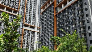 A high-rise residential building with multiple balconies, surrounded by lush greenery and a paved walkway. - Apartmen Pakuwon by Fiola Homes (Jawa Barat)