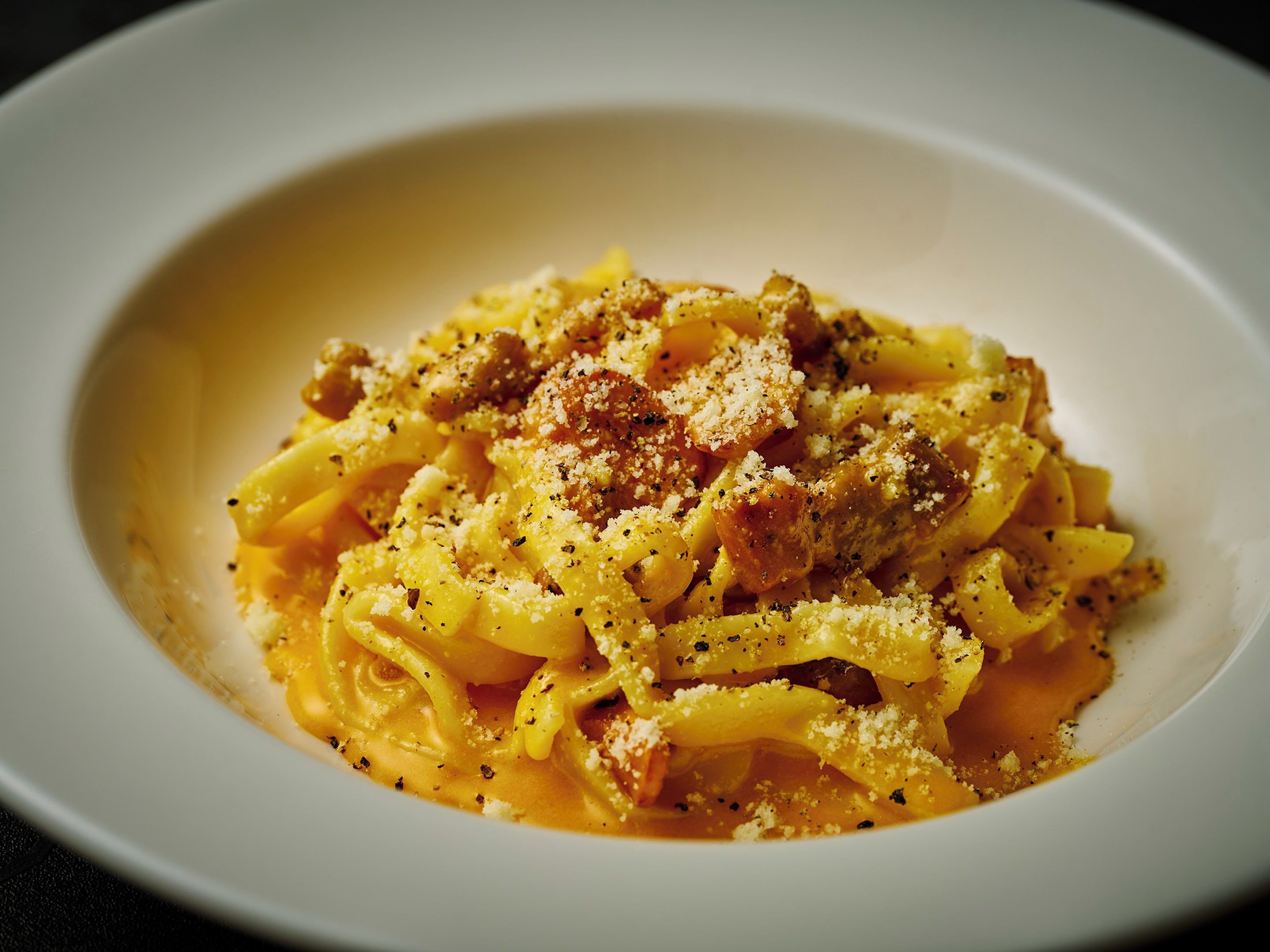 A bowl of pasta with a creamy sauce, topped with grated cheese and herbs.