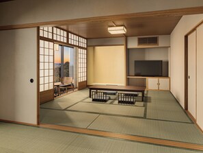 A traditional Japanese room with tatami flooring, a low table, a television on a shelf, and a sliding door with a view. - ARIMA ONSEN WARAYA JINSEN (Kobe)