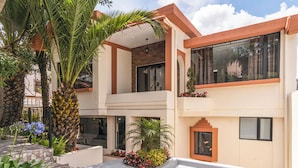 A modern two-story building with a balcony, large windows, and a stone pathway. - Casa BuenaVida  (Quito)