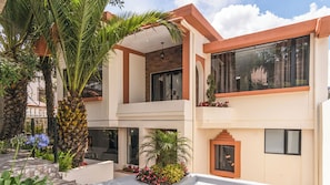 A modern two-story building with a balcony, large windows, and a stone pathway. - Casa BuenaVida  (Quito)