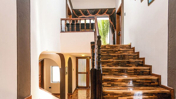 A staircase with a unique wood pattern, a wooden handrail, and a view of a room with a window and a door.
