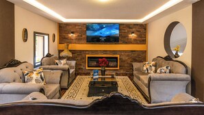 A living room with a fireplace, sofas, a coffee table, and a flat-screen TV mounted on a brick wall. - Casa BuenaVida  (Quito)