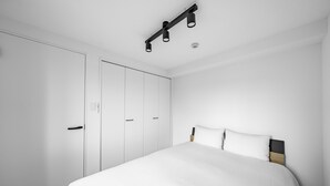 A bedroom with a bed, white wardrobe, and a ceiling light fixture. - ASTAGE CHITOSE SUEHIRO 103 (Chitose)