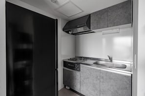 Una cocina moderna con un refrigerador negro, electrodomésticos de acero inoxidable y un horno empotrado.