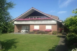 A two-story house with a balcony, a front lawn, and a small patio area. - Prinsepark 1st floor (Domburg)