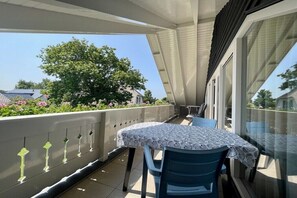A balcony with a table and chairs, a railing with decorative elements, and a view of a tree and buildings. - Prinsepark 1st floor (Domburg)