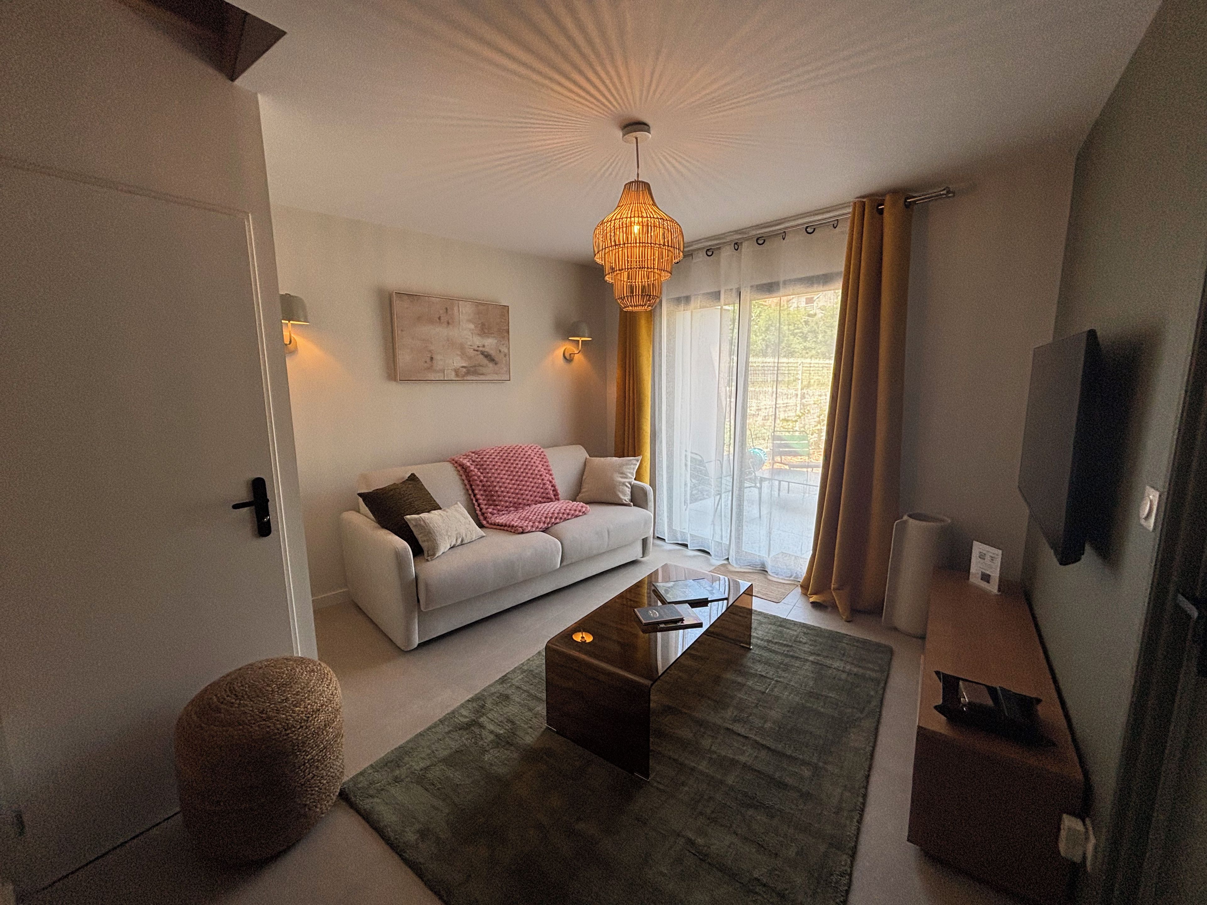 A modern living room with a sofa, coffee table, and a hanging light fixture.