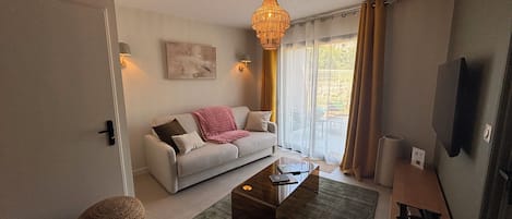 A modern living room with a sofa, coffee table, and a hanging light fixture.