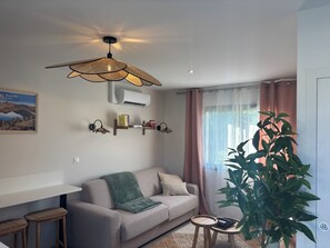 A living room with a sofa, a table, a plant, and a ceiling fan.