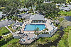 A resort with a central pool, lounge areas, and a surrounding landscaped area. - PGA National Cottage | Pool, Patio & Golf (Palm Beach Gardens)