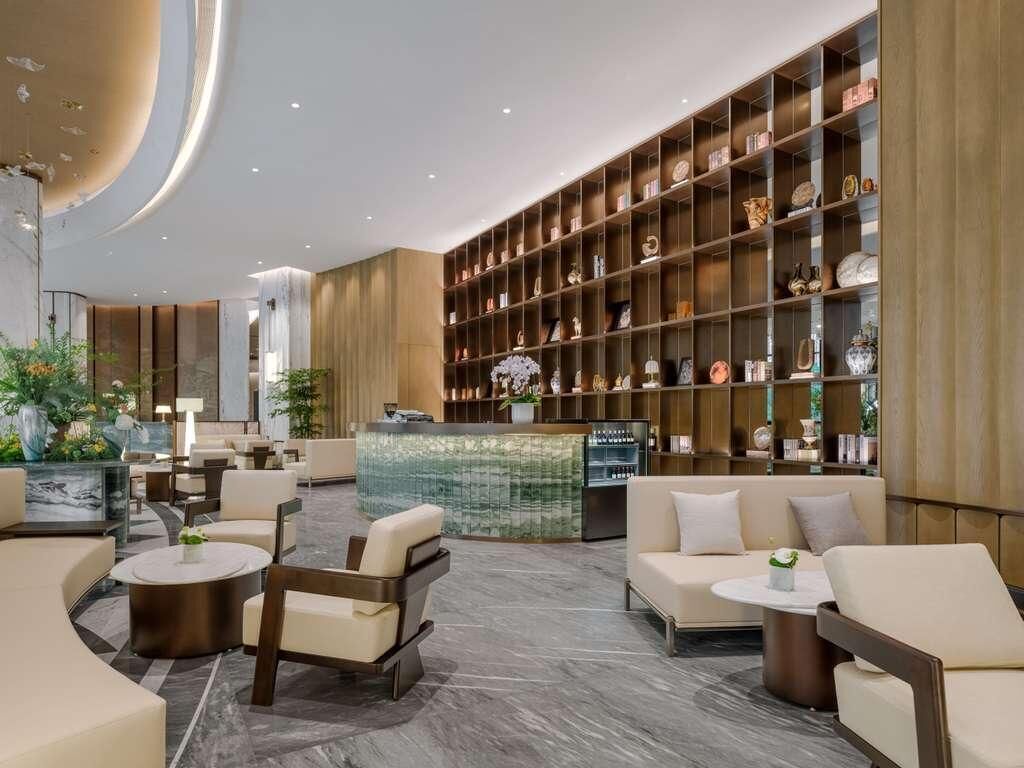 Eine moderne Lobby mit Sitzgelegenheiten, einem Empfangsbereich und einem großen Regal mit Dekoration.