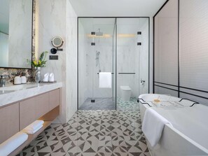 Un baño moderno con tocador de mármol, cabina de ducha de vidrio y suelo estampado.