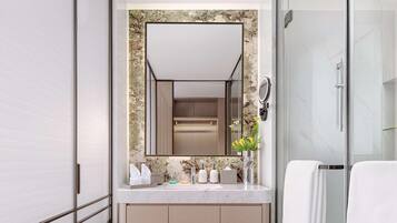A modern bathroom with a large mirror, a glass shower enclosure, and a marble countertop.