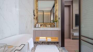 A modern bathroom with a marble wall, a large mirror, a bathtub, and a patterned floor.
