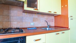 A kitchen with a gas stove, sink, and wooden cabinets. - Casa Libeccio - Pistis - wifi - Pet Friendly (Arbus)