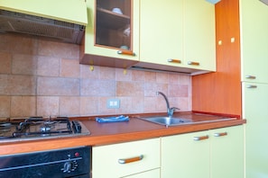 A kitchen with a gas stove, sink, and wooden cabinets. - Casa Libeccio - Pistis - wifi - Pet Friendly (Arbus)